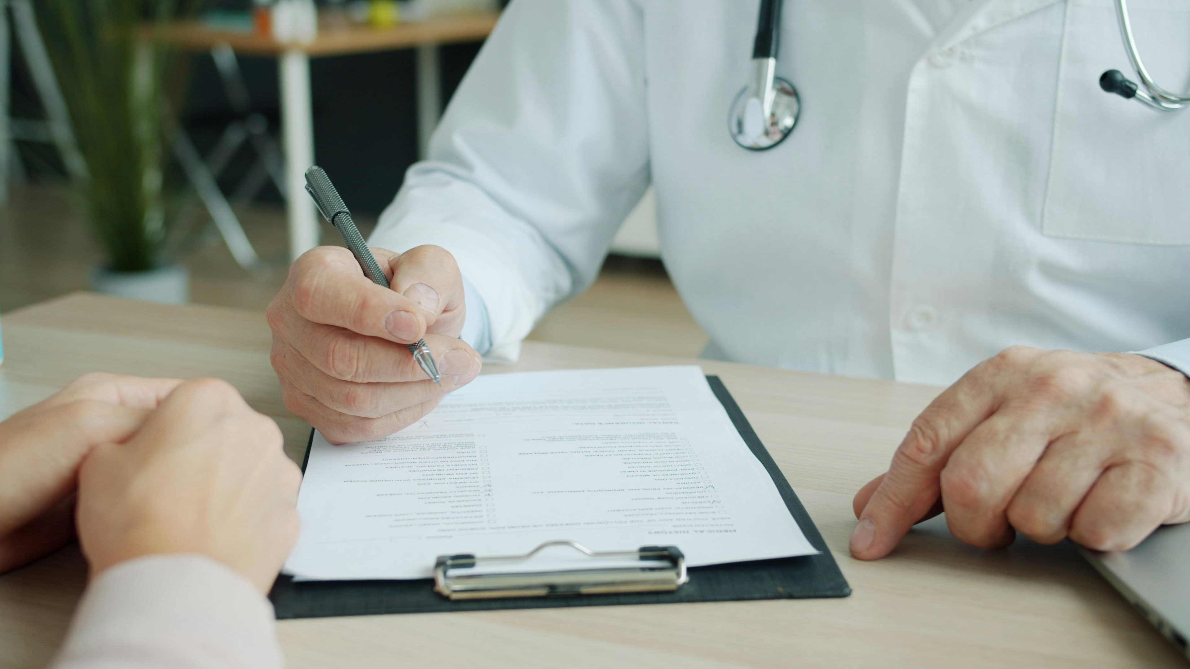 Médico em consulta preenchendo a documentação com o paciente